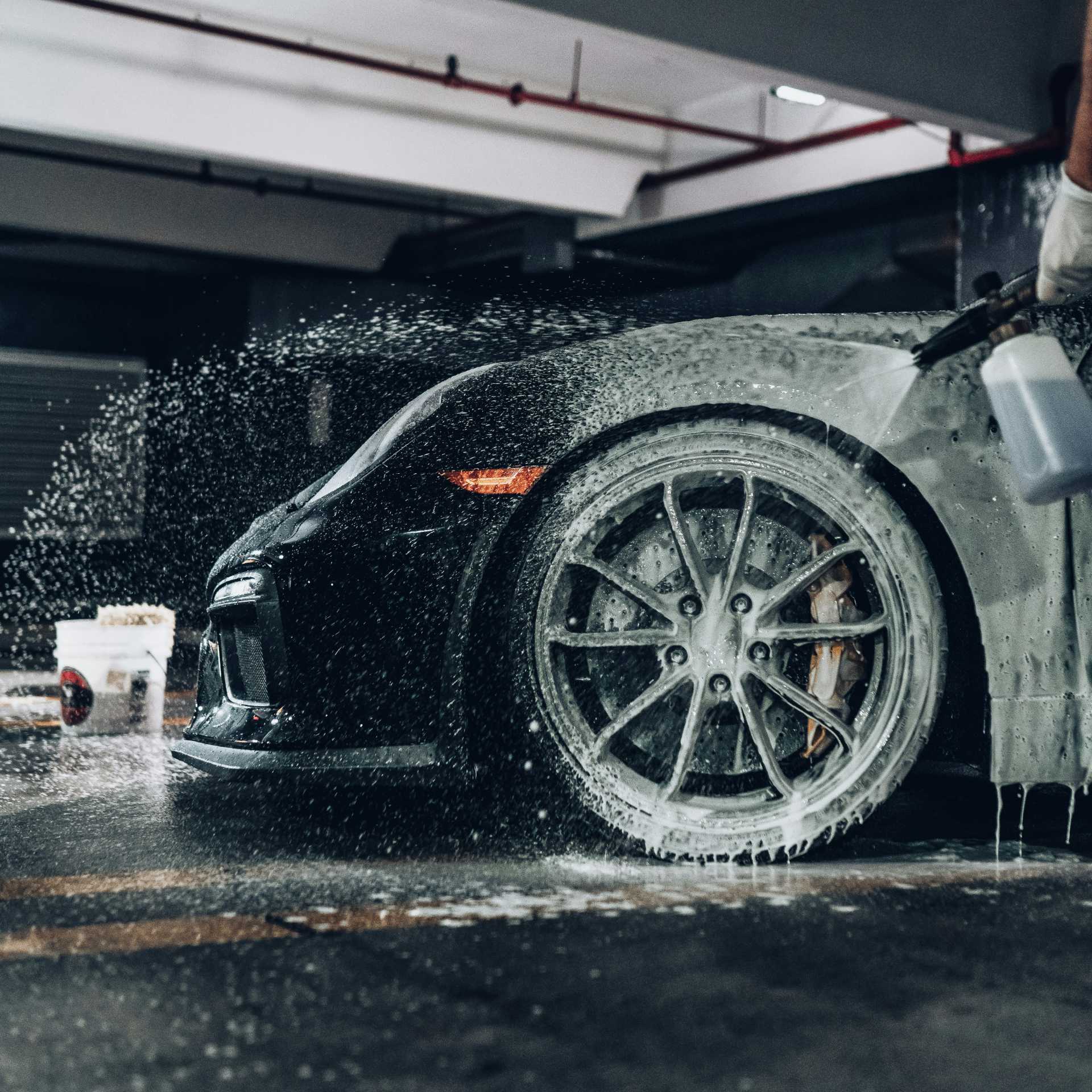 Car wheel getting foamed and pressure washed