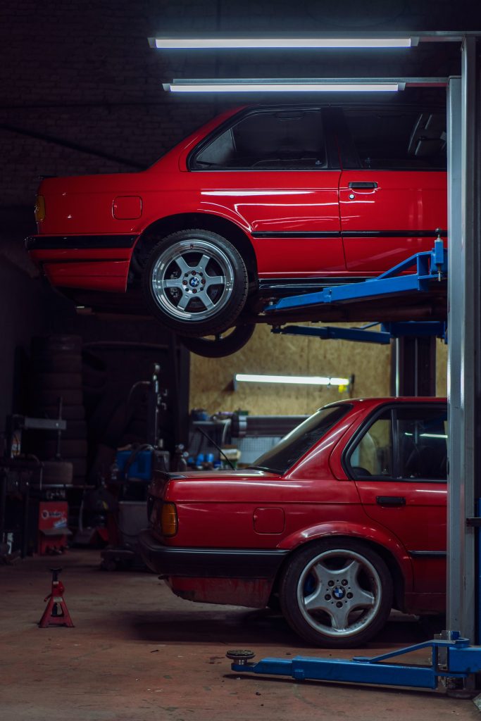 Red car raised on lift in garage